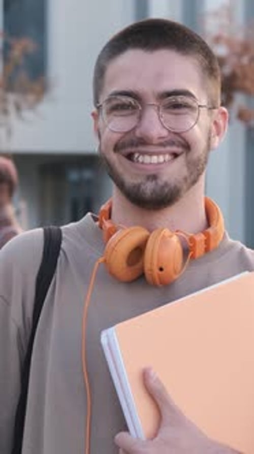 Smiling Young Adult Student with Headphones and Notebook