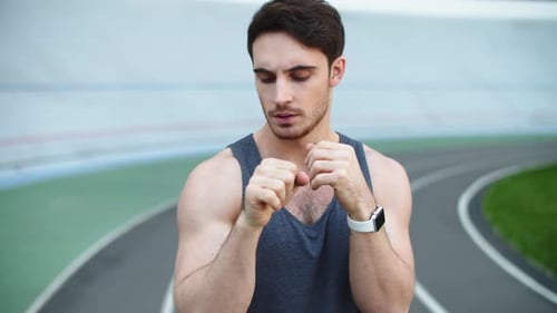 Athletic man warming up wrists before run outdoors