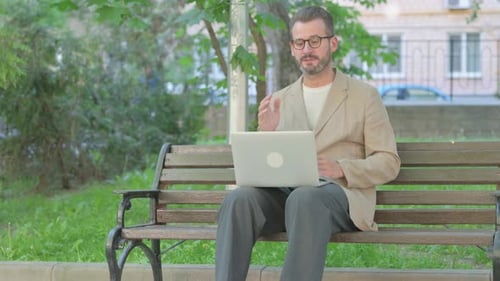 Man Using Laptop on Park Bench Video Call
