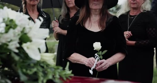 Sad, casket and people at graveyard for funeral, goodbye and mourning for loss