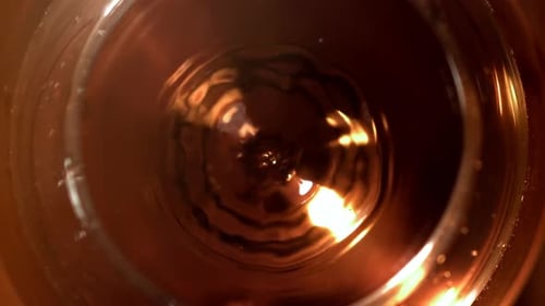 Ein Tropfen fällt in ein Glas Cognac, das mit einer Hochgeschwindigkeitskamera mit 1000 Bildern pro Sekunde gefilmt wurde