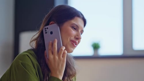Woman Talking on Phone and Writing at Desk