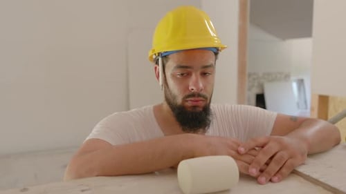Bearded Construction Worker in Hard Hat Leans on Wood