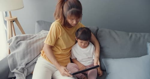 Mother and Child Sitting Together on Sofa with Tablet