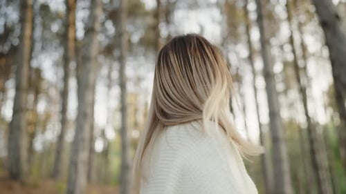 Smiling Young Woman Enjoying a Sunny Day in a Pine Forest