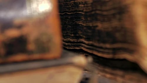 Extreme close-up pan of sides of worn ancient books, shallow DOF