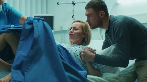 En el hospital, una mujer en trabajo de parto empuja para dar a luz, los obstetras la ayudan, su cónyuge la toma de la mano