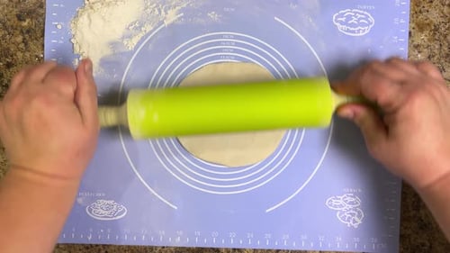 Rolling out round pieces of raw dough with a rolling pin to make patties. Top view.