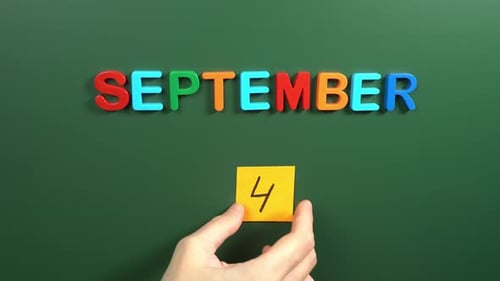 Hand sticking a sticker 4 September calendar day on school board. 4 date of September. Fourth day