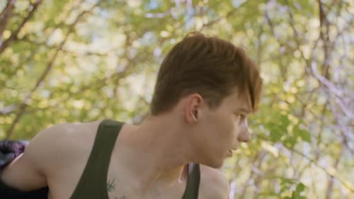 Soldier Unzips Jacket and Pulls It Off While Looking Around in Awe in Forest