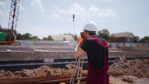Back Shot of Professional Construction Worker Using Theodolite Surveying Optical Instrument Man