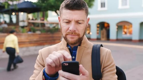Business, man and reading with phone in city for travel, schedule update and social media post