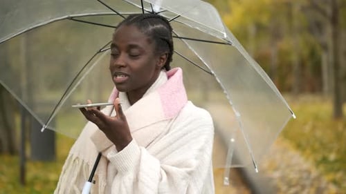 Woman Speaking Into Phone in Autumn Park