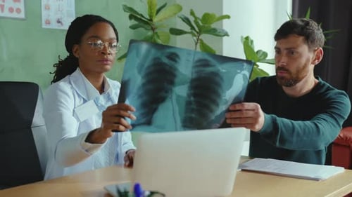 Doctor showing x-ray results to her male patient