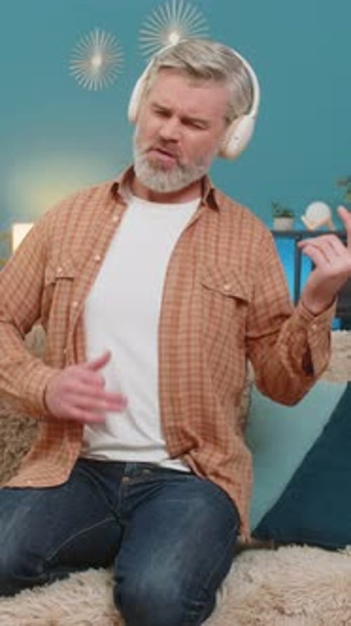 Man Sitting on Couch Pretends to Play Guitar