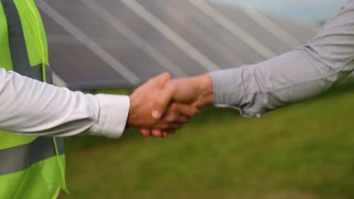 Engineer and Investor Shaking Hands at Solar Panel Farm