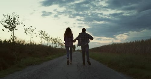 Back View: Happy Young Couple Screaming, Celebrating, Running on a Road Next
