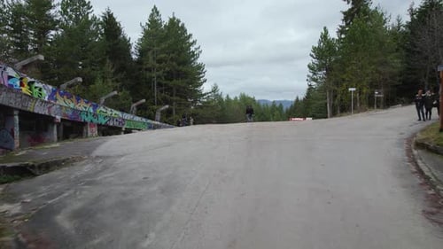 Flying underneath old bobsled from the 84 winter Olympics in Sarajevo and revealing forest and a cit