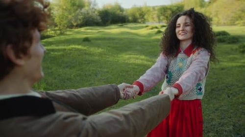 Happy Girl Holding Hands and Spinning with Boyfriend on Green Lawn