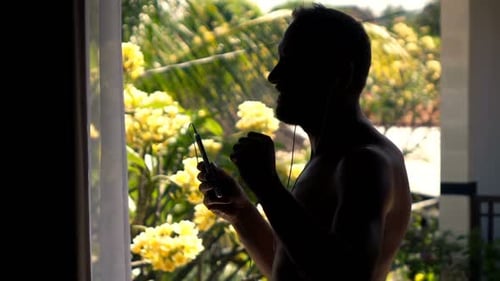 Silhouette of Man Listening to Music and Dancing on Terrace, Super Slow