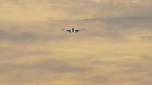 Airplane Landing Against Dramatic Cloudy Sunset Sky