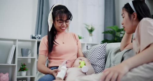 Mother Feeding Baby with Friend in Living Room