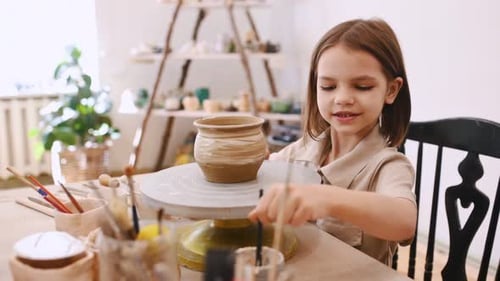 Girl Painting Pottery on Wheel in Art Studio