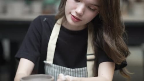Young women is making earthenware at workshop.