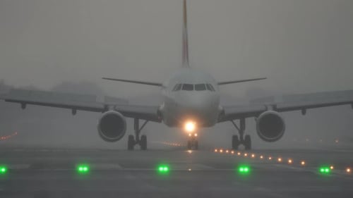 Airplane Landing on Runway with Fog and Illuminated Lights Creating a Dramatic Atmosphere