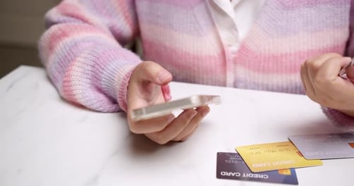 Close-up woman's hand holds a smartphone and selects a mockup Bank credit card for online shopping s
