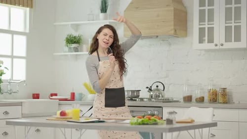 Happy Woman Dancing and Singing in Kitchen