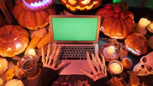 Man in death costume typing on keyboard sinister halloween holiday ads decorated with carved pumpkin