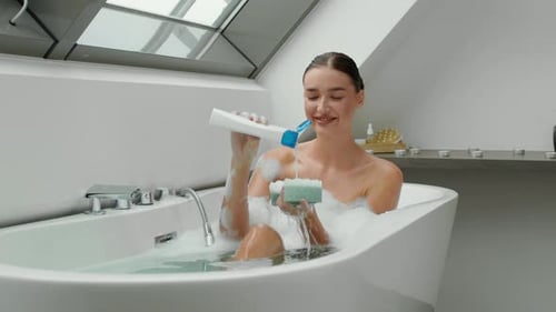Woman Relaxing in Bubble Bath With Sponge