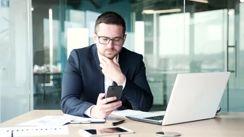 Man in Suit Using Smartphone at Desk