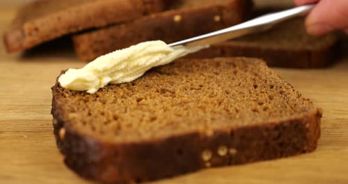 Spreading Creamy Butter on Slice of Brown Bread