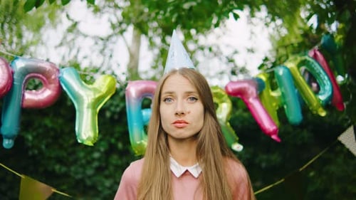 Woman With Party Hat Stands Sadly By Banner