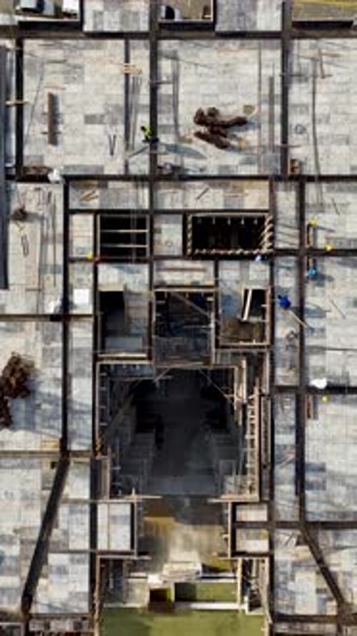 Vídeo vertical trabajadores en un proyecto de construcción preparando marcos de acero y bloques de piedra para