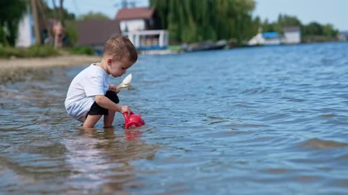 Small kid having fun at river sand beach. Boy playing on the beach with water.