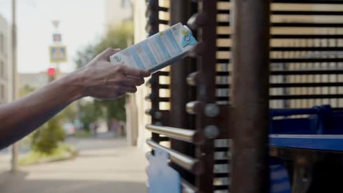Woman Throws Used Pack of Drink Into Trash Bin on Street