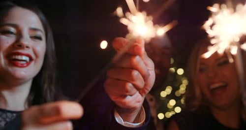 Group, sparkler and party fun with friends celebrating New Years eve at night while having fun