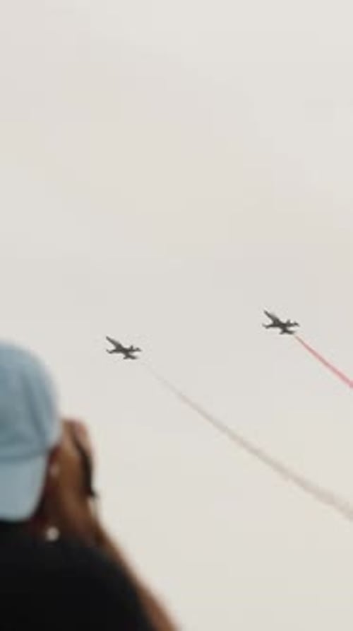 Vertical video. Three fighter jets fly against the backdrop of mountains, leaving trails.