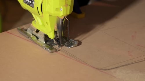 Close-up of electric jigsaw in action, men's hand cutting up wood board with a jigsaw in 4K