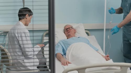 Senior Patient Talking to Doctor when Getting IV Injection from Worker in Clinic
