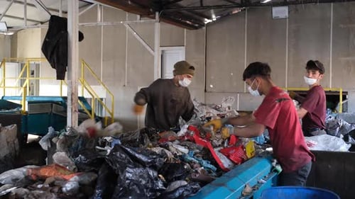 Workers Sorting Garbage Moving Down The Belt At A Recycling Plant