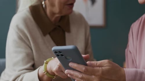 Senior Women Looking at Smartphone Together Indoors