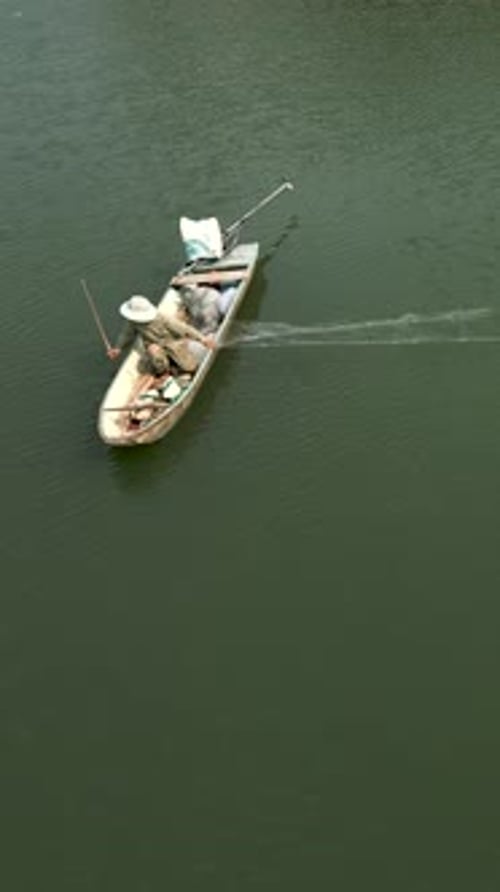 Pêcheur étalant les filets depuis un petit bateau au milieu d'une grande rivière au Vietnam