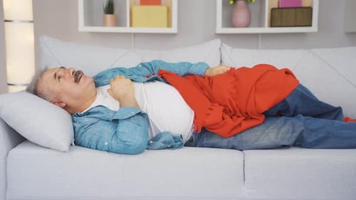 Man Experiencing Pain Lying on Couch Indoors