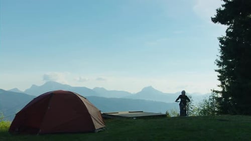 A mountain biker arrives at campsite and gets in his tent