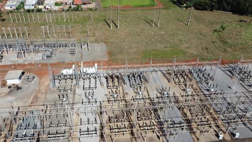 Aerial tracking shot passing over a transformer station with a slow pan up to reveal a suburban area