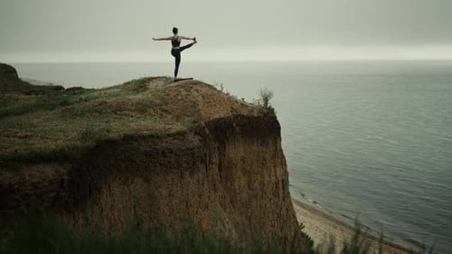 Femme gracieuse faisant du yoga et des asanas, un équilibre sur un tertre de plage. Fille flexible debout sur une jambe...